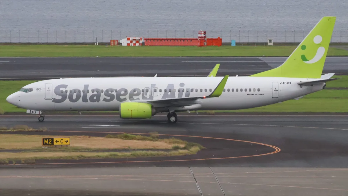 A Solaseed Air Boeing 737-800 with a lime green tail and engine taxiing at Haneda Airport, in 2026