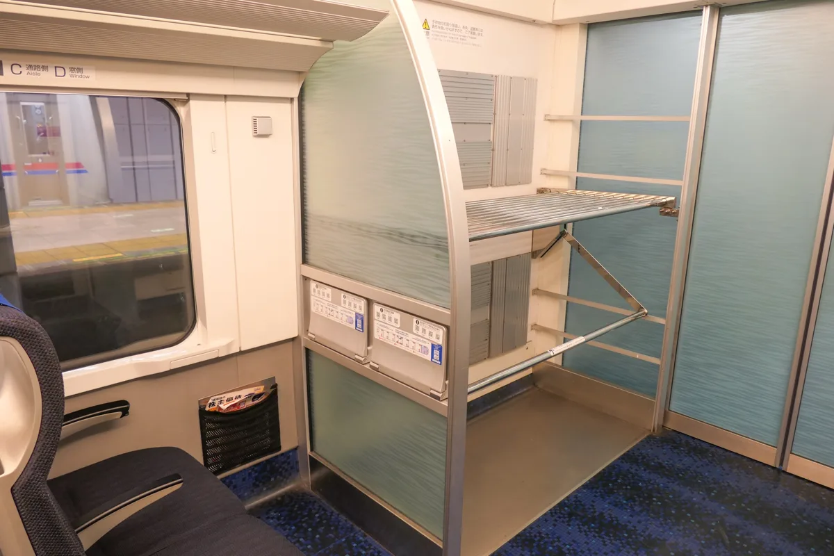 The luggage rack near the door of a Keisei AE series Skyliner car, with two shelves for suitcases, in 2023