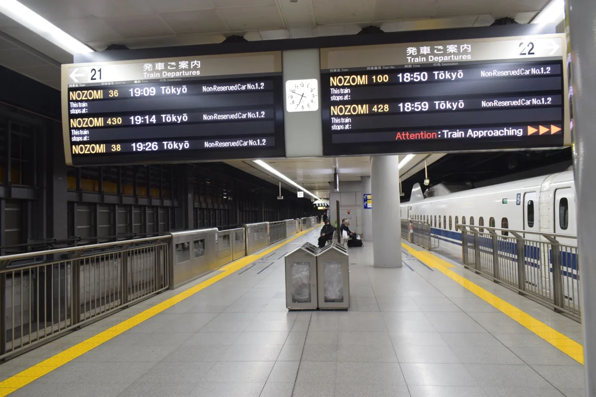 Departure boards on the Tokaido Shinkansen platform at Shinagawa Station listing Nozomi trains to Tokyo, with non-reserved.