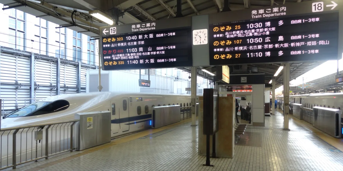 Departure boards on Shinkansen platforms 18 and 19 at Tokyo Station listing Nozomi and Hikari trains, with an N700 series.