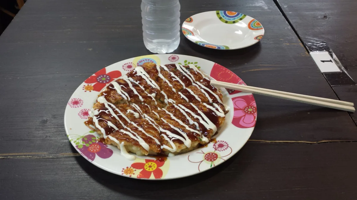 An Osaka-style okonomiyaki with sauce and mayonnaise on a plate in a restaurant in Osaka, in 2015