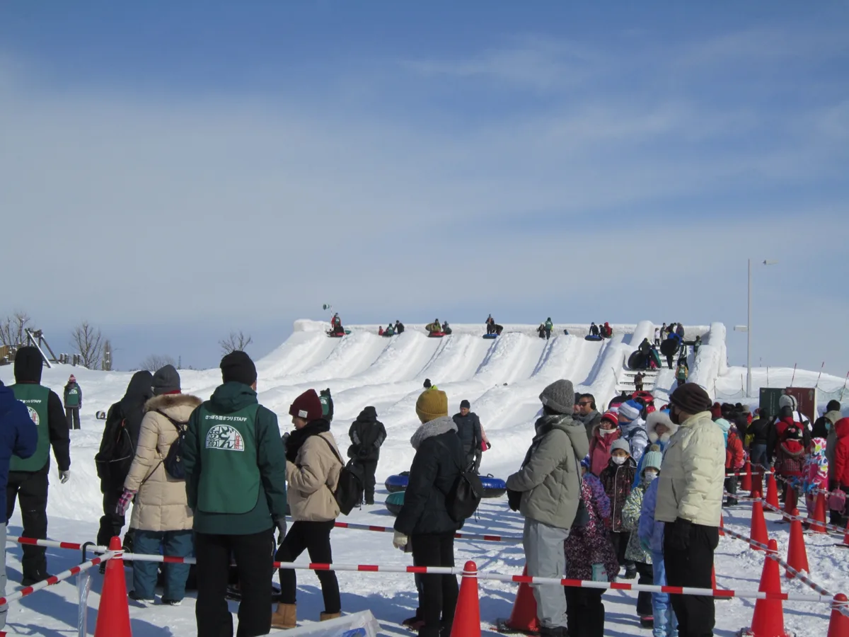 Families queueing in the snow for the tube slider at the Tsudome site of the Sapporo Snow Festival in February 2020