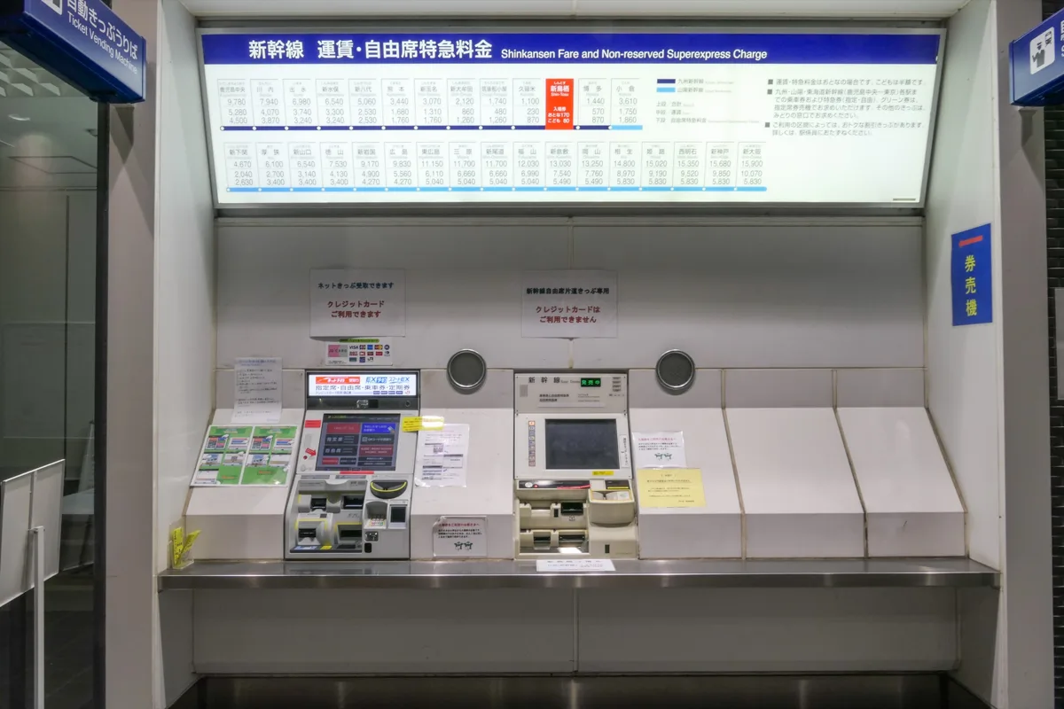 Shinkansen ticket machines at Shin-Tosu Station under a board of Shinkansen fares and non-reserved seat charges, in 2024