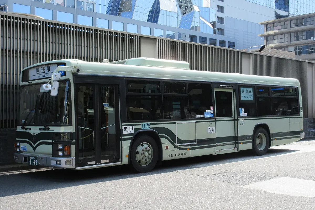 A Kyoto City Bus marked Out of Service parked on a street with city buildings behind it