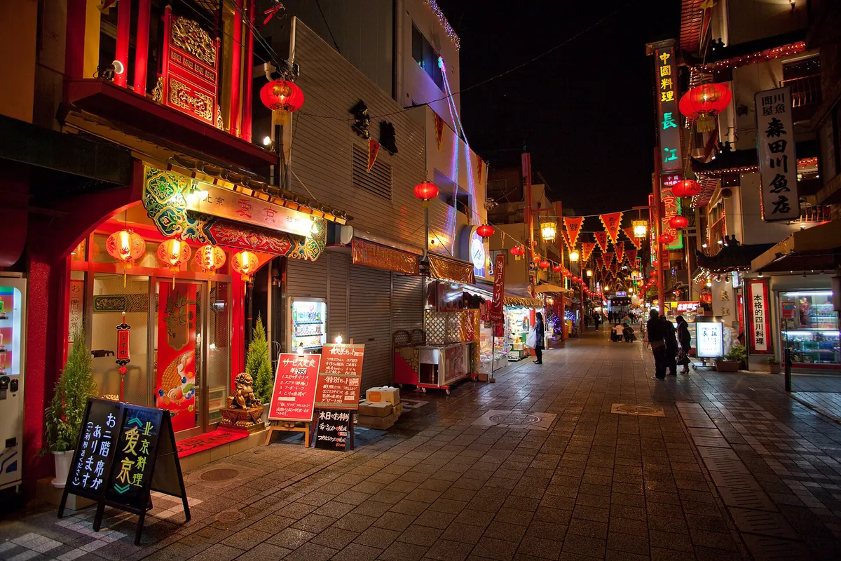 A Nankinmachi Chinatown street in Kobe at night, lined with red lanterns and lit shop signs
