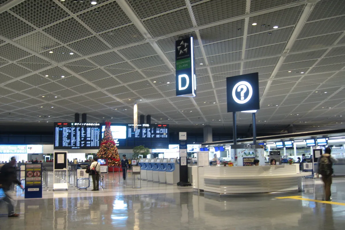 A departure hall at Narita Airport Terminal 1 with an information counter, overhead signage and a Christmas tree