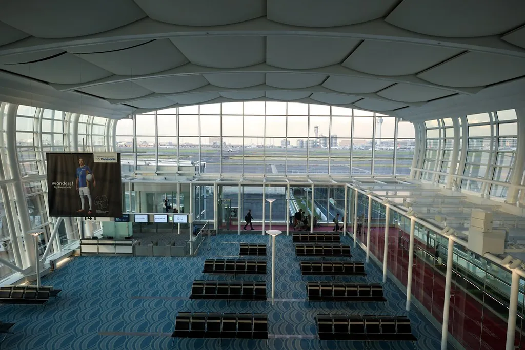 A wide hall with large windows and rows of seating overlooking the tarmac at Haneda Airport's international terminal