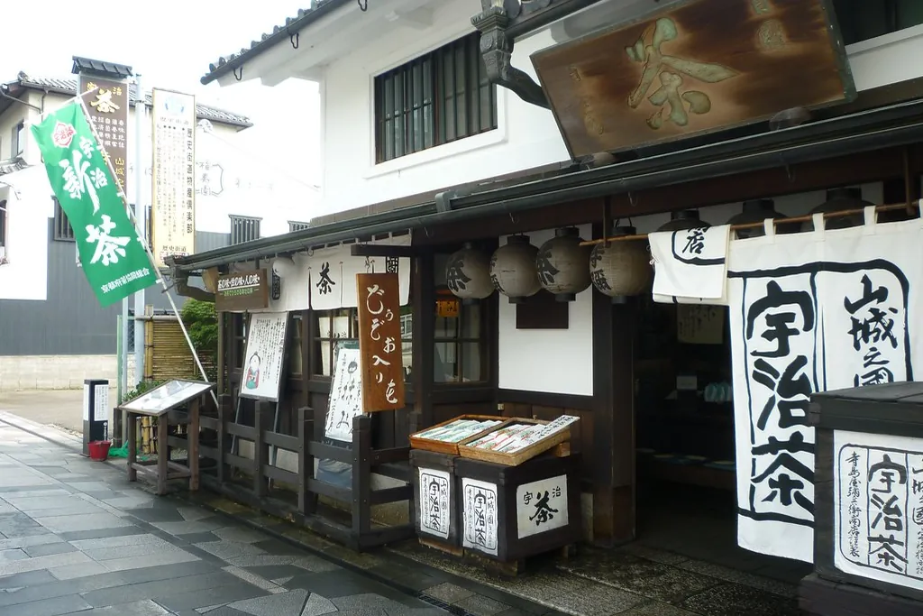 A traditional tea shop front with hanging curtains and banners reading Uji tea on a stone-paved street in Uji, Kyoto