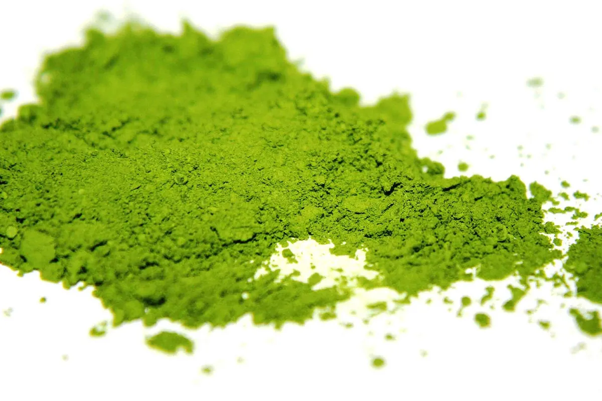 A pile of bright green matcha powder on a white background.