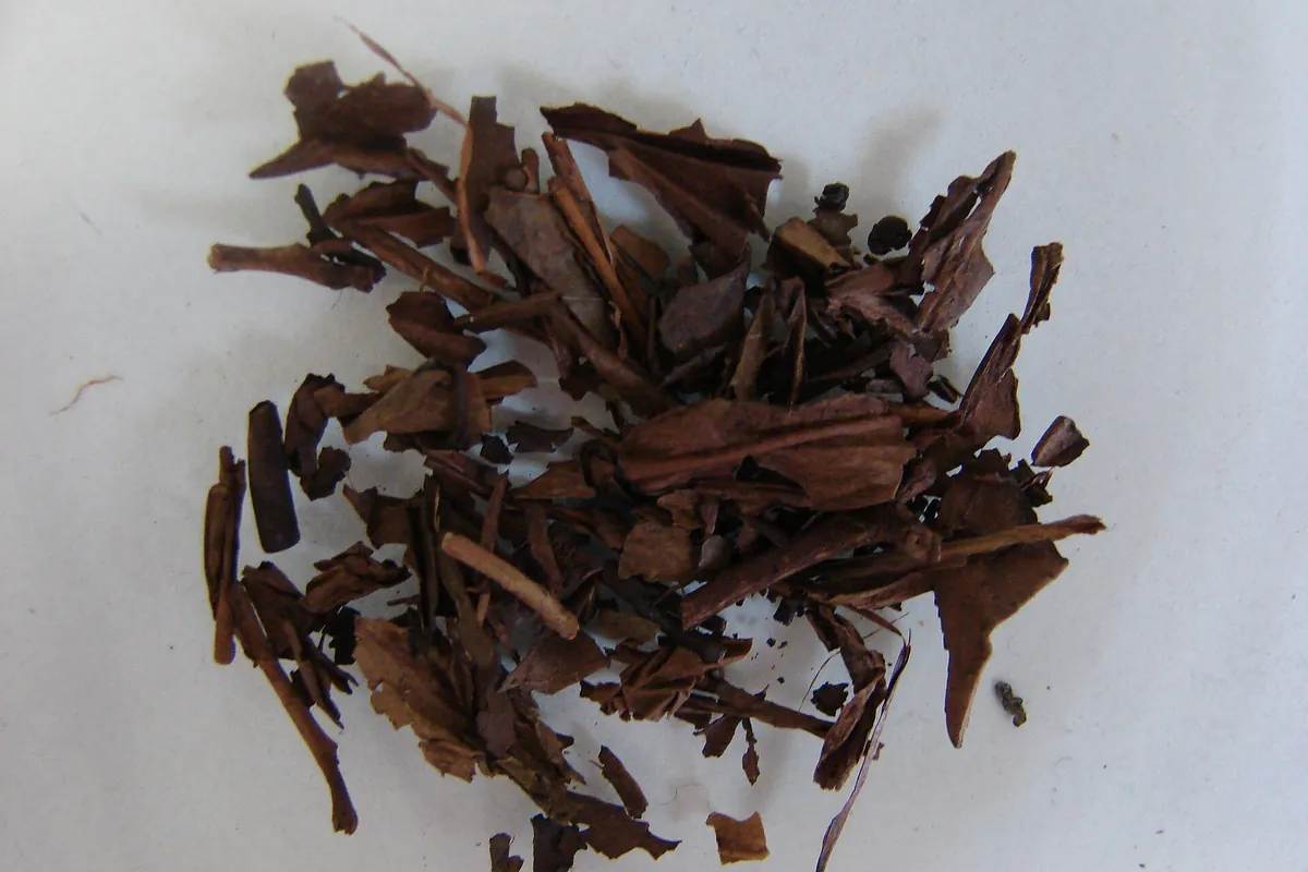 A pile of dried, brown roasted hojicha tea leaves on a white surface.
