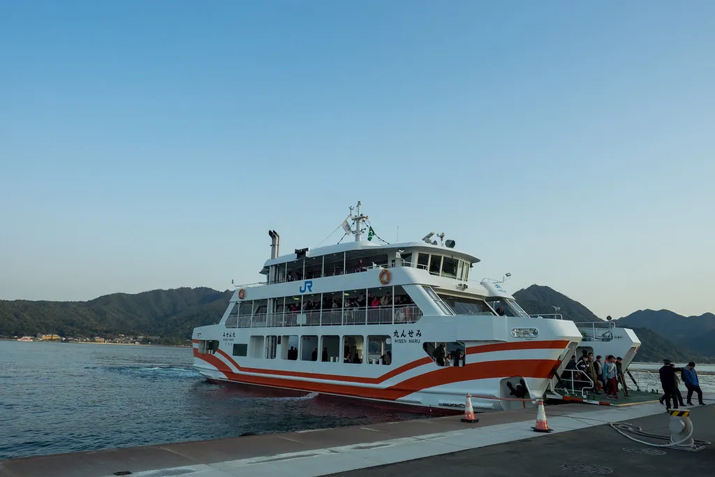 The JR ferry Misen Maru docked at a pier with passengers disembarking and mountains across the water