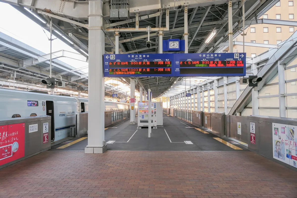 Departure boards for Mizuho and Sakura trains at a Kagoshima-Chuo Station platform, with a train stopped alongside