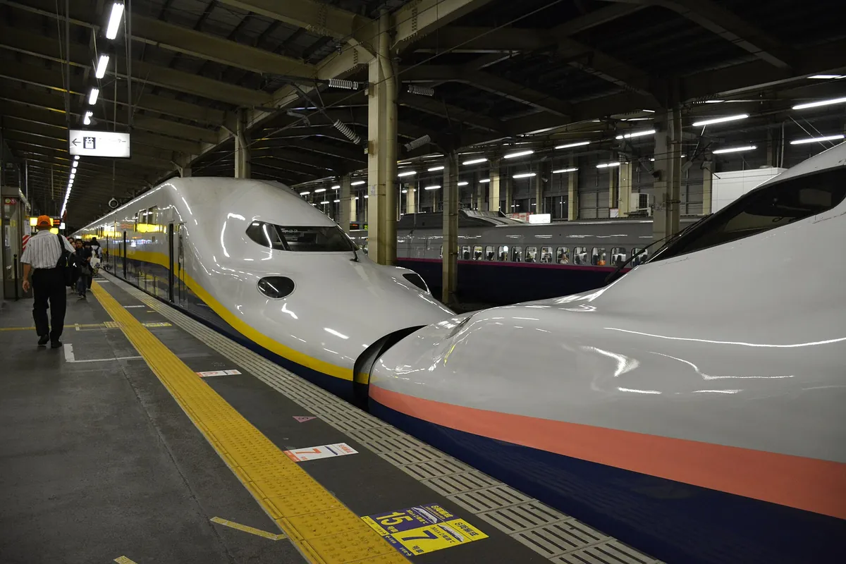 黄色とオレンジのラインが入った白い新幹線が、越後湯沢駅のホームに停車している様子