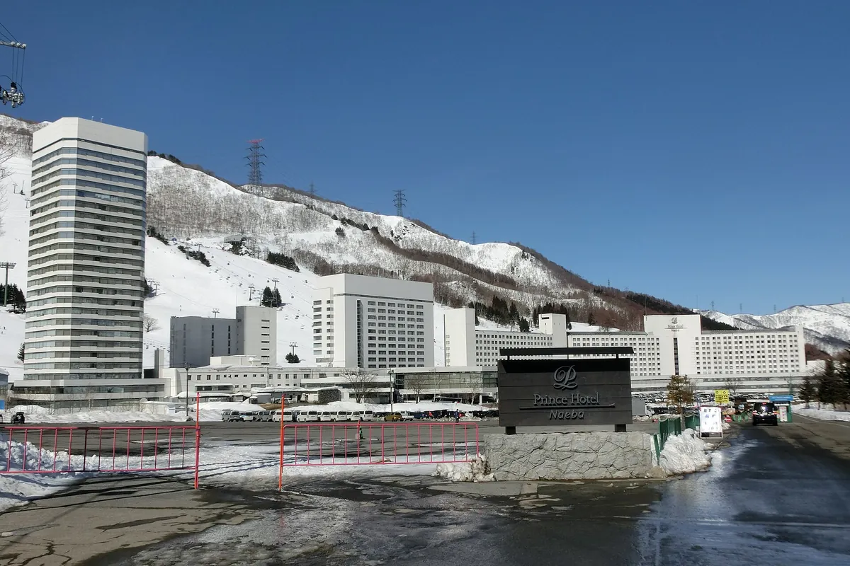 看板のある苗場プリンスホテルの建物と、雪に覆われた山の斜面