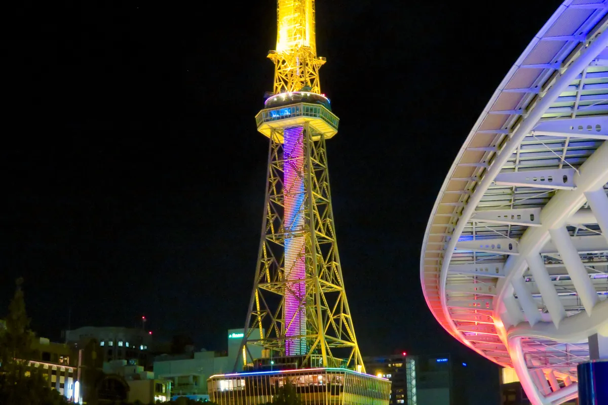 オアシス21のガラス屋根のそばで、夜に金色にライトアップされた名古屋テレビ塔