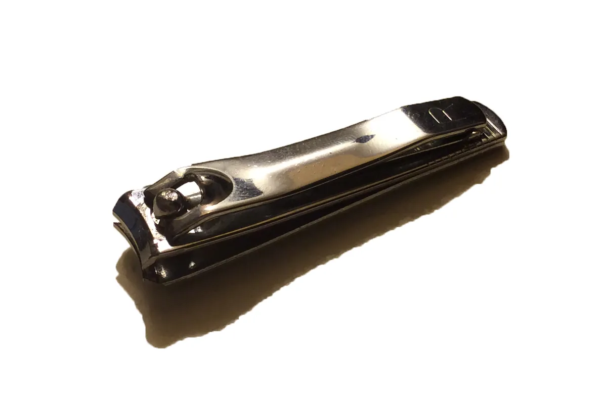 A closed silver nail clipper photographed at an angle on a white background