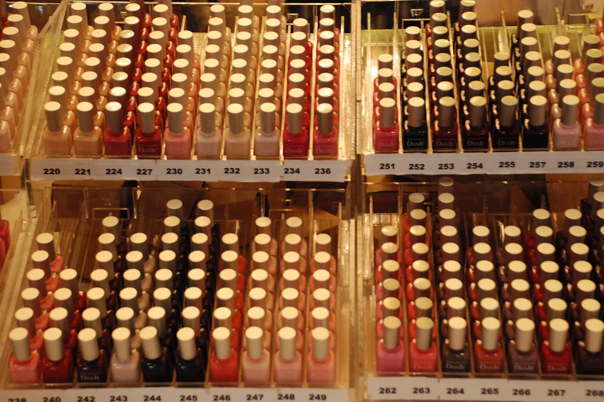 Rows of nail polish bottles with numbered labels on display shelves in a shop