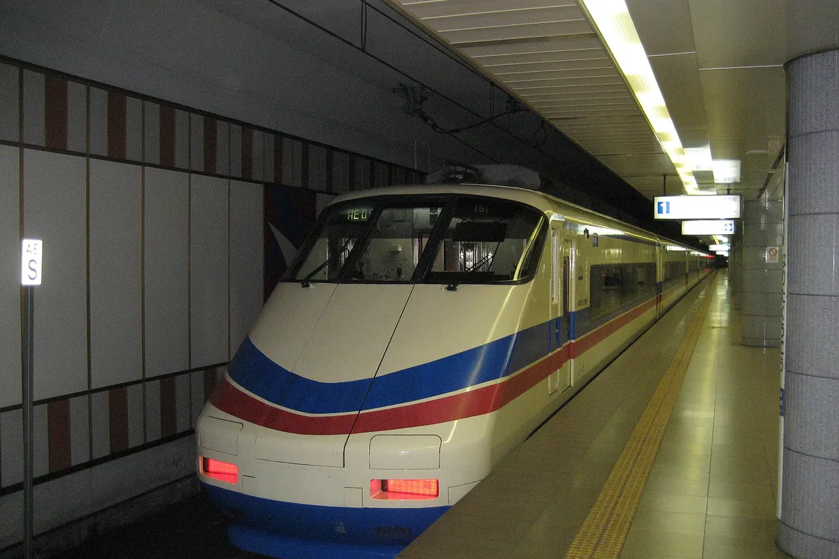 Keisei Skyliner train with a white body and blue and red stripes at Narita Airport Station