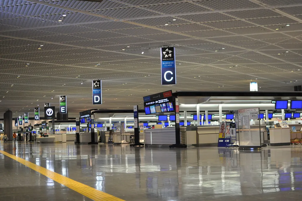 An empty terminal hall at Narita Airport Terminal 1 with overhead signs marked C, D and E above check-in counters