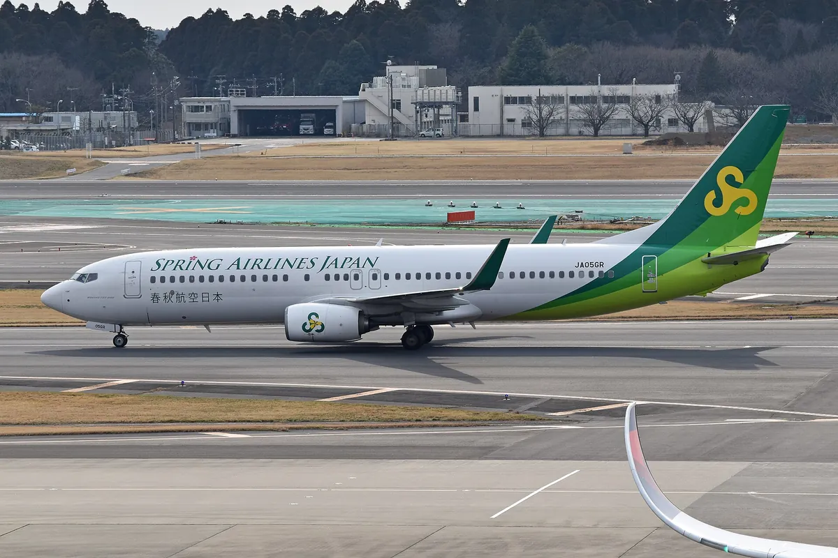 A Spring Airlines Japan Boeing 737 with a green tail, registration JA05GR, taxiing at Narita Airport