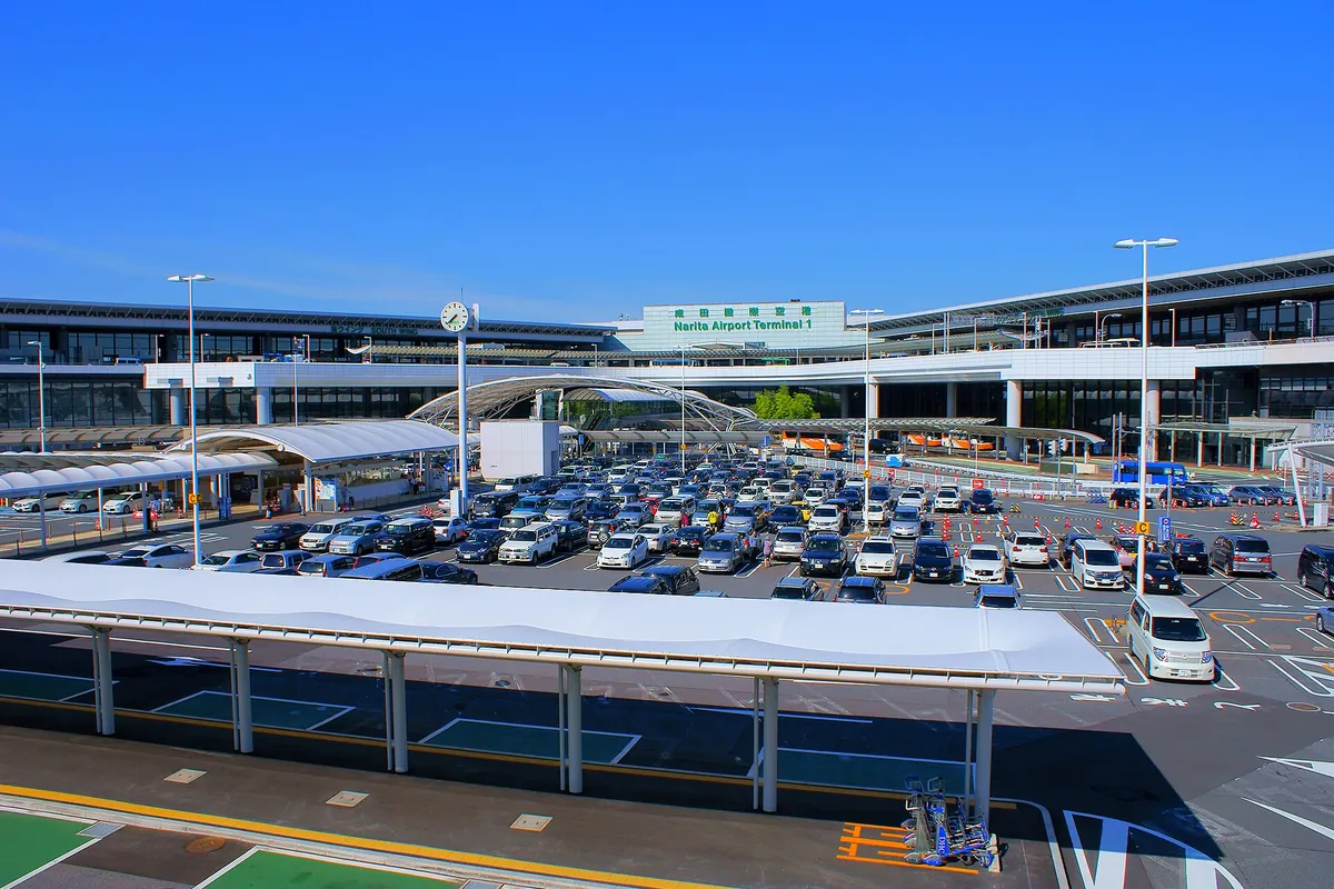 成田空港ターミナル1の外観。成田空港ターミナル1の看板と、車で埋まった駐車場が見える