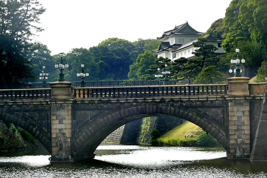 木々に囲まれた東京の皇居にある、伏見櫓とともに写る二重橋の石橋