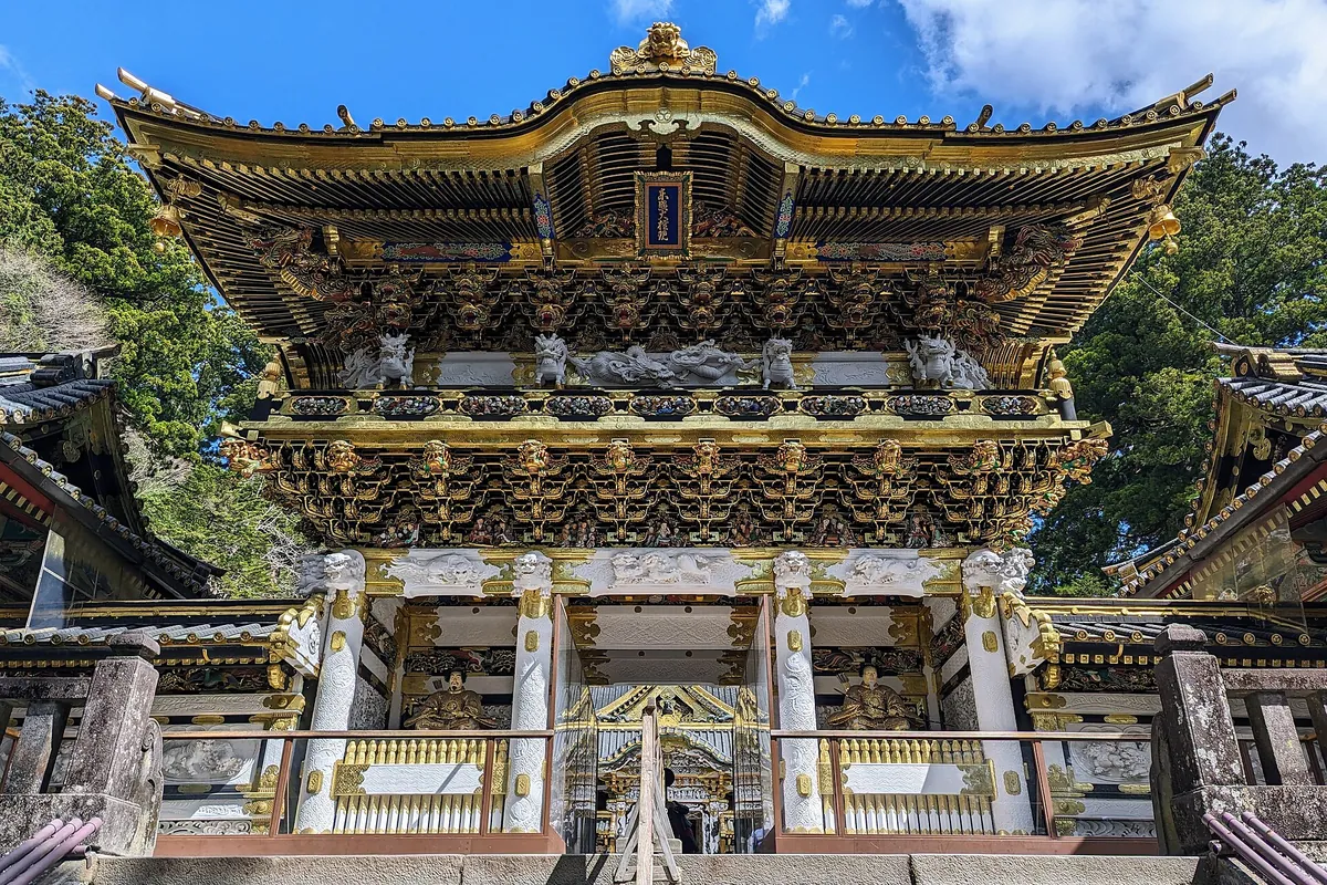 The ornate Yomeimon gate at Nikko Toshogu shrine, with intricate white and gold carvings covering its facade