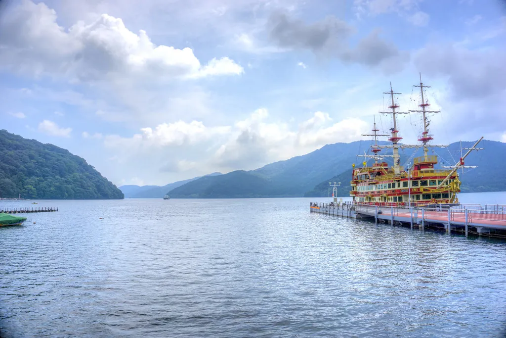 A Hakone pirate ship sightseeing boat docked at a pier on Lake Ashi, with mountains in the background
