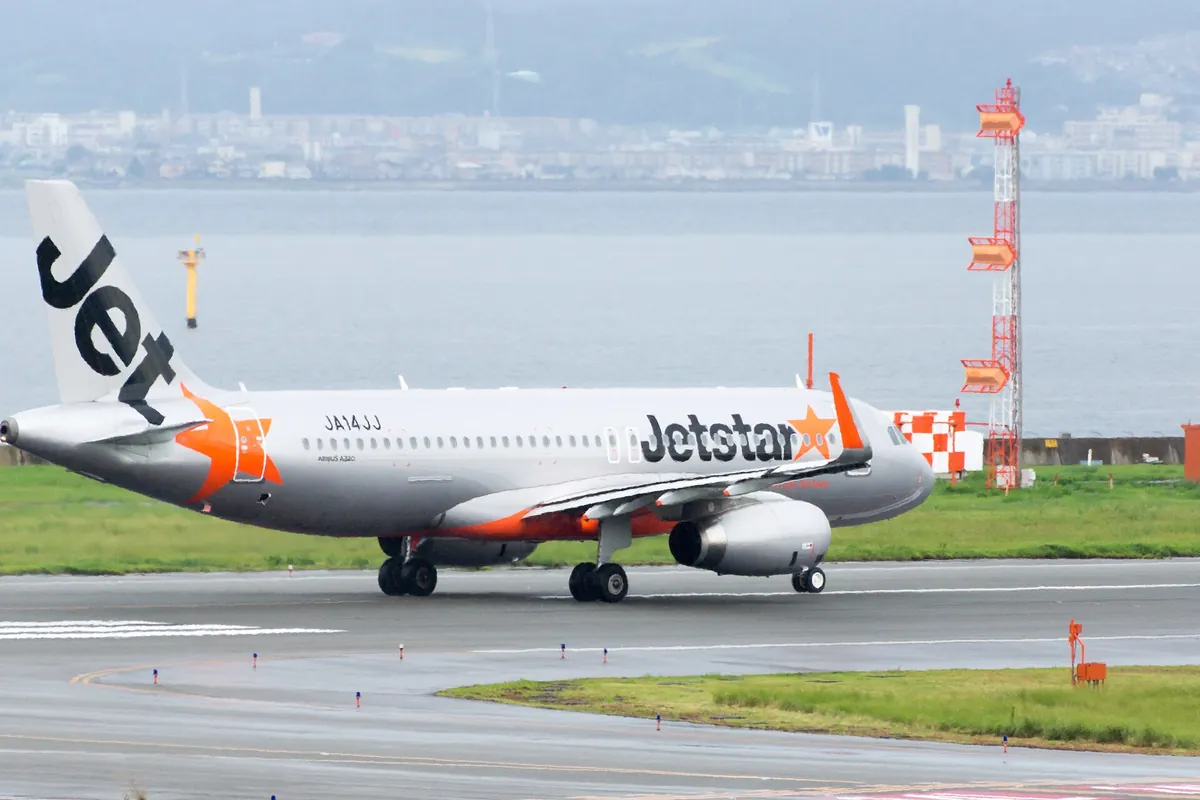 A Jetstar Japan Airbus A320 taxiing at an airport with the sea in the background