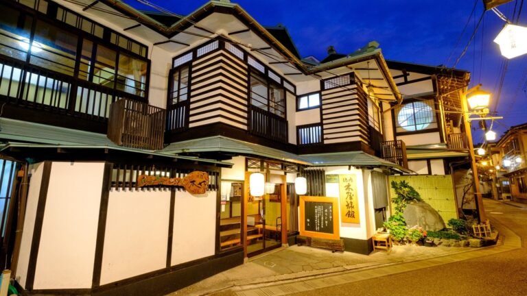 The lit wooden front of a traditional ryokan in Misasa Onsen at dusk