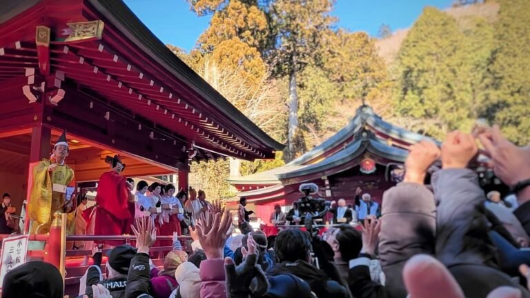 日本节分祭上，人群举起双手接神社舞台上撒下的豆子