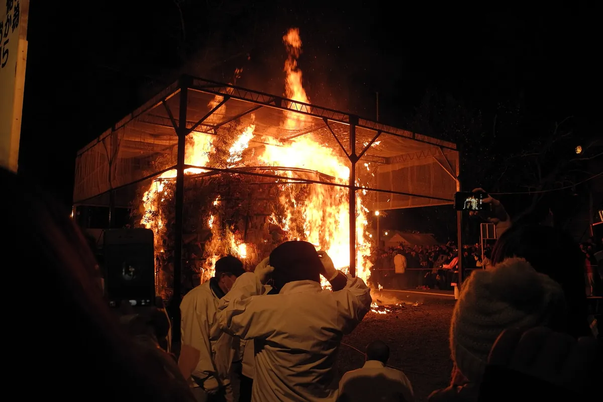 京都吉田神社节分火祭中，金属笼里燃烧的大篝火和身穿白衣的人