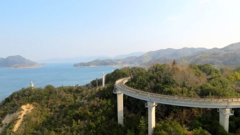 瀬戸内海を見下ろす緑豊かな丘の斜面を通る高架のサイクリング橋。遠くには島々が見える