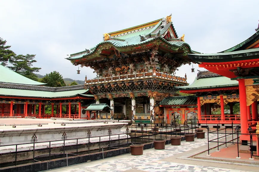 耕三寺の赤と金の装飾が施された山門。彫刻の装飾と緑の瓦屋根がある