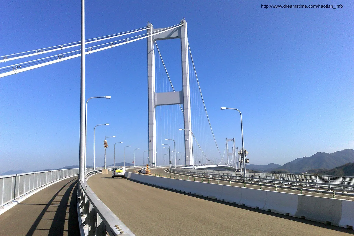 しまなみ海道の吊橋で、道路沿いに分離された自転車・歩行者用の道があり、上には白い高い主塔が見える