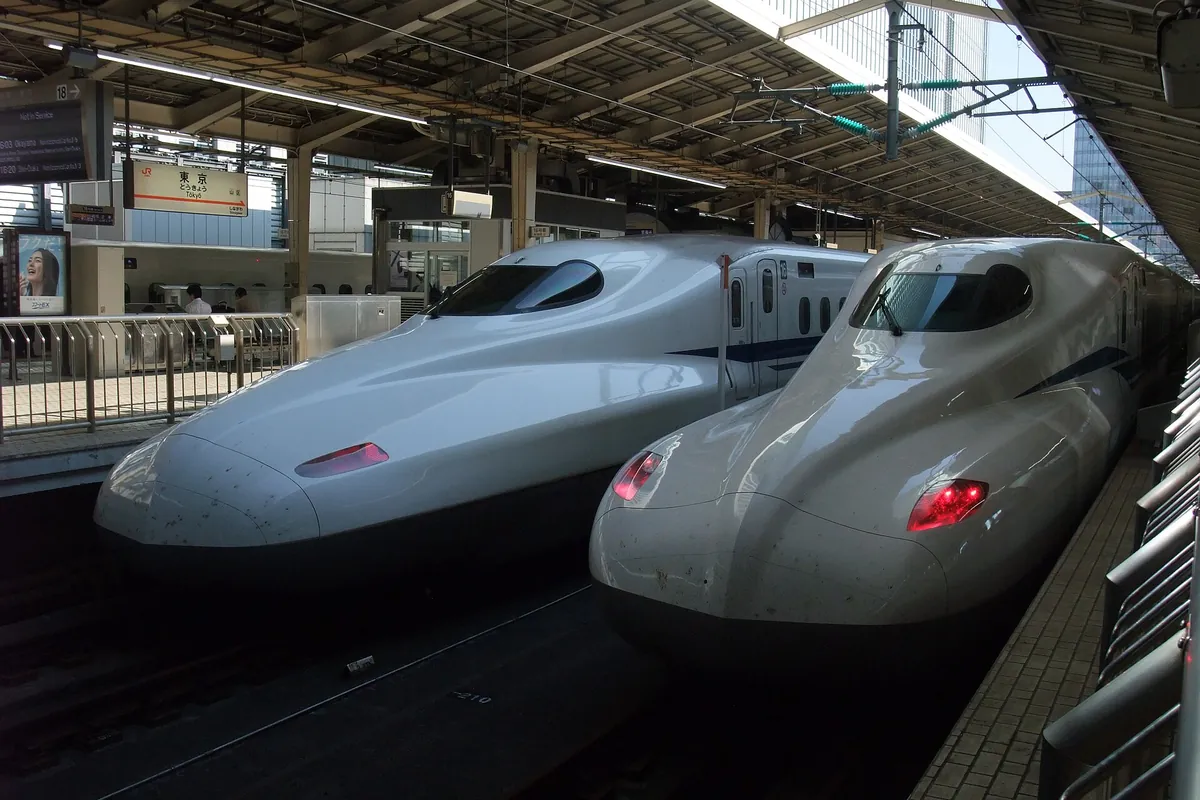 Two white Shinkansen trains standing side by side at a platform, with a sign reading Tokyo