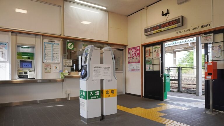 ENTRY and EXIT automatic ticket gates beside a ticket counter and vending machine at a JR station in Akita
