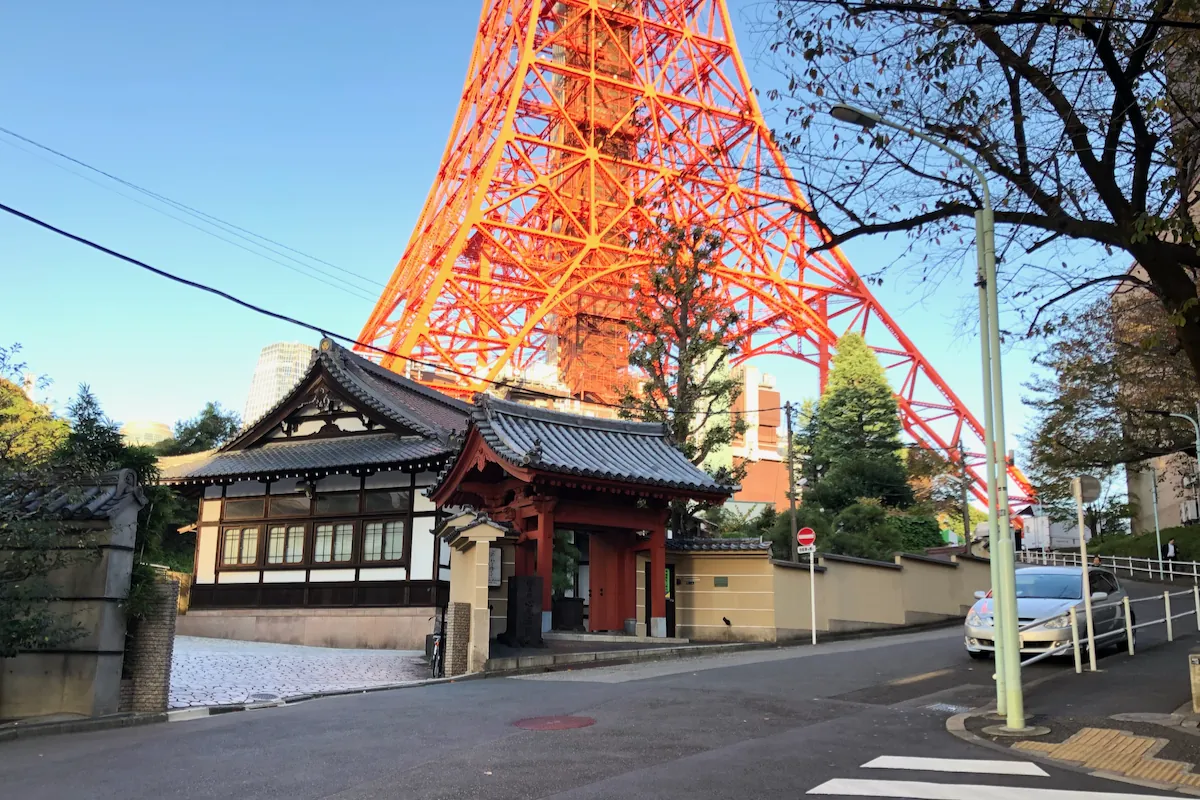 Tokyo Tower rising above a traditional gate and street in Minato City, Tokyo