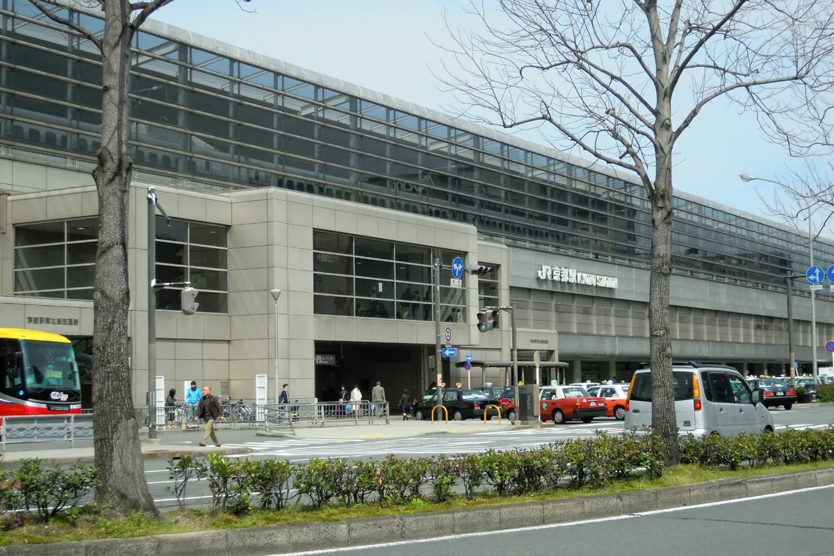 Exterior of the JR Kyoto Station building seen from the street, with bare trees and a bus at the left