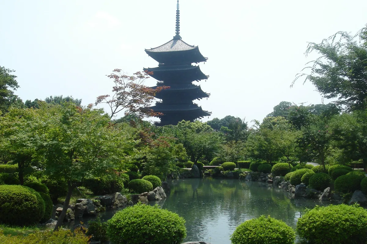 Five-storied pagoda of To-ji temple rising above green trees and a garden pond