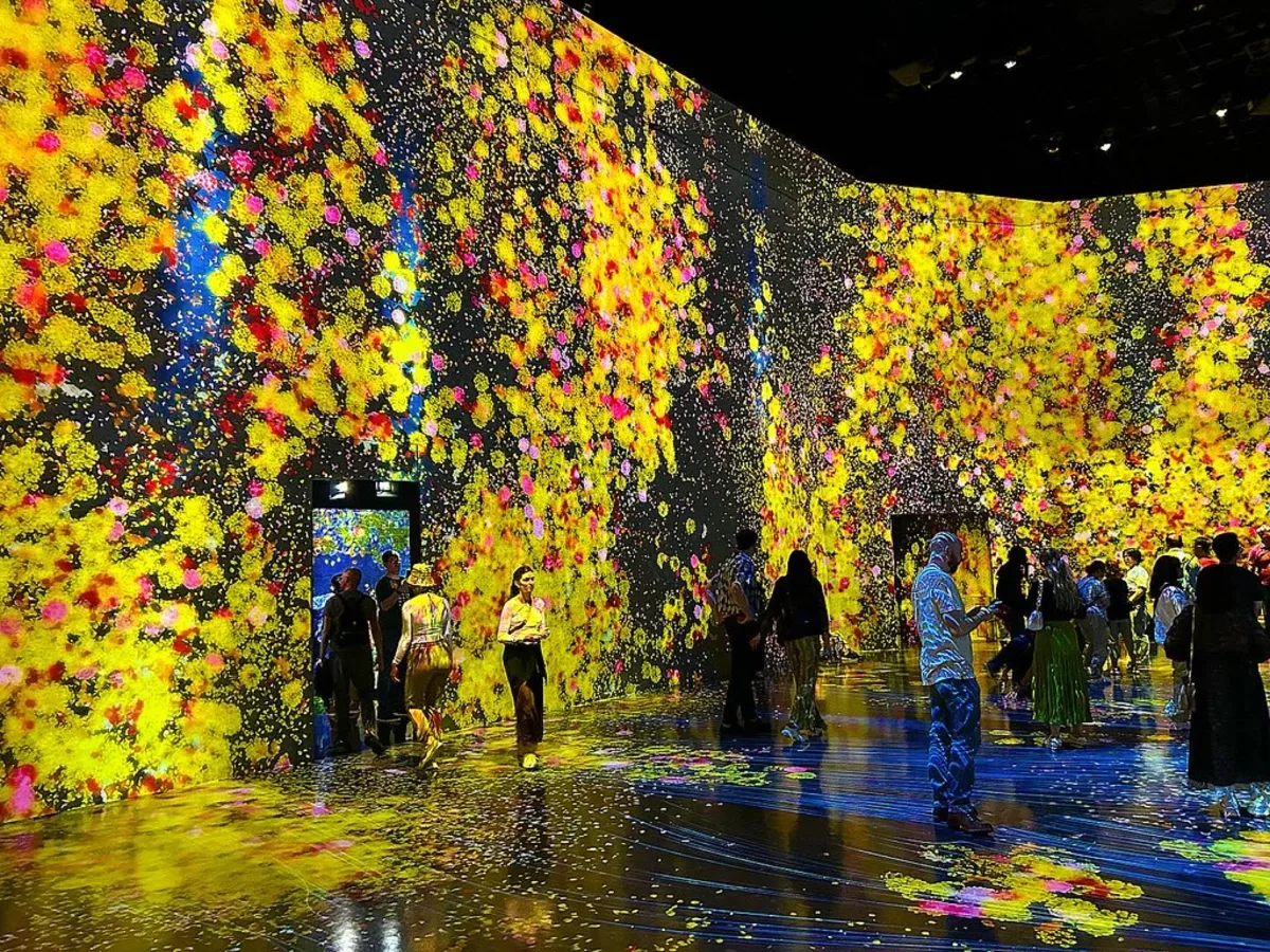 Room of projected yellow flowers with visitors walking through