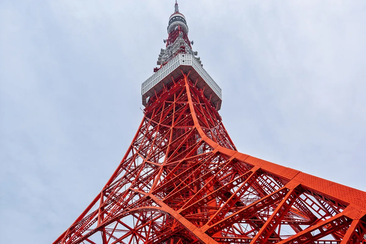 Low-angle view looking up at the red and white lattice structure of Tokyo Tower in Minato, Tokyo