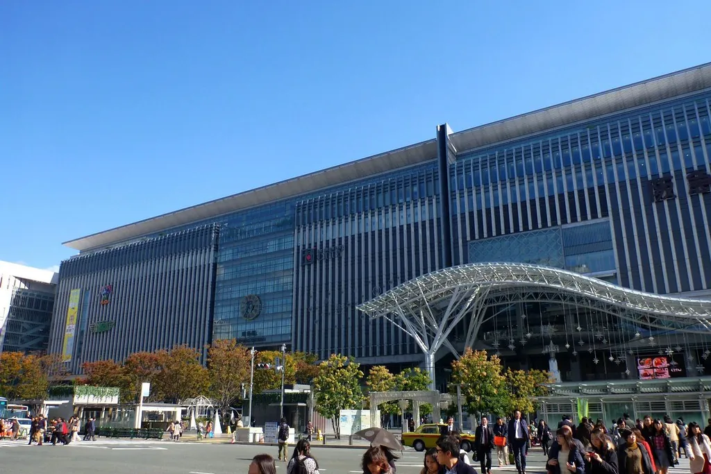 Exterior of Hakata Station building in Fukuoka, Japan, with pedestrians crossing in the plaza in front
