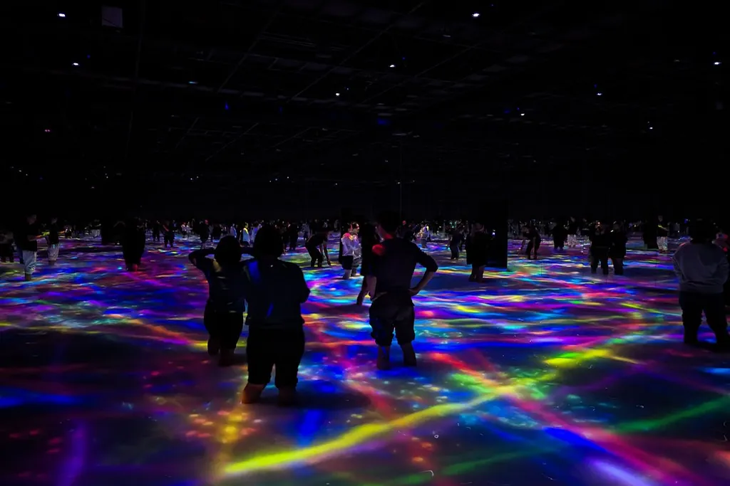 Visitors standing on a floor lit with colorful crisscrossing light patterns at teamLab Planets, Tokyo
