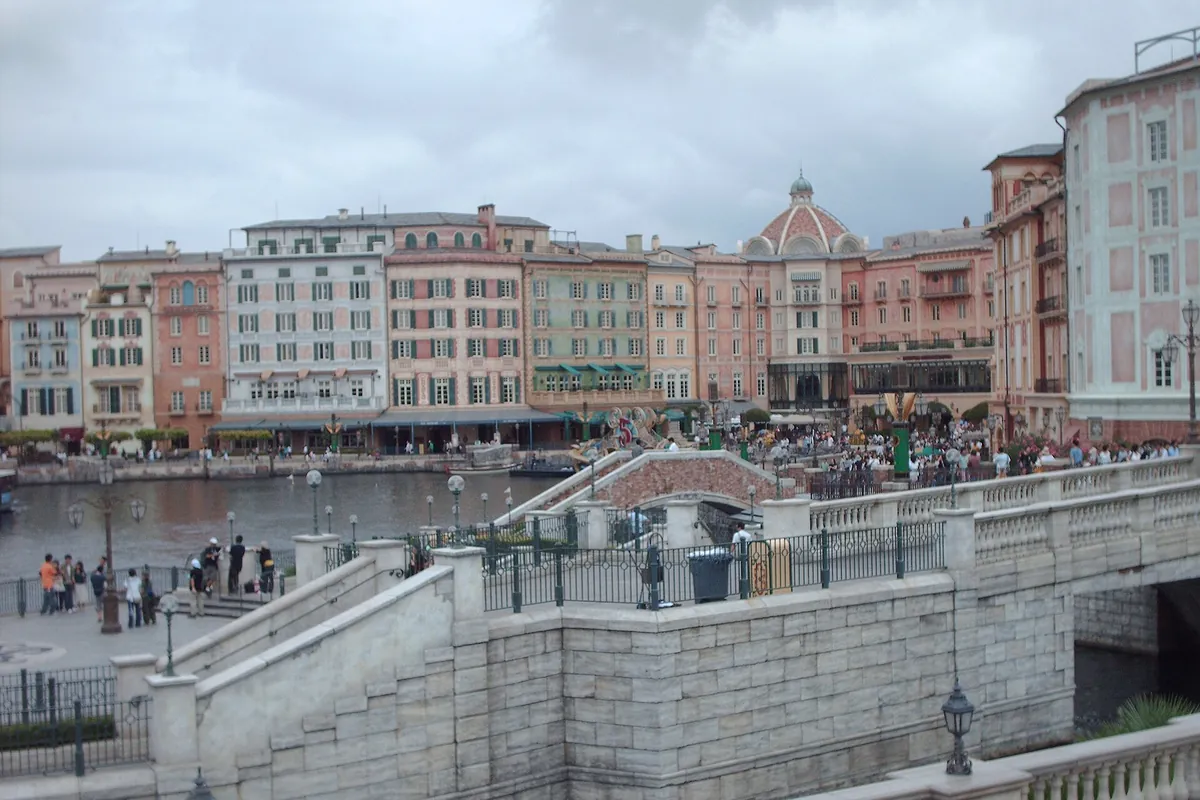 Mediterranean Harbor at Tokyo DisneySea, with Mediterranean-style buildings along the water, a stone bridge, and crowds of gu