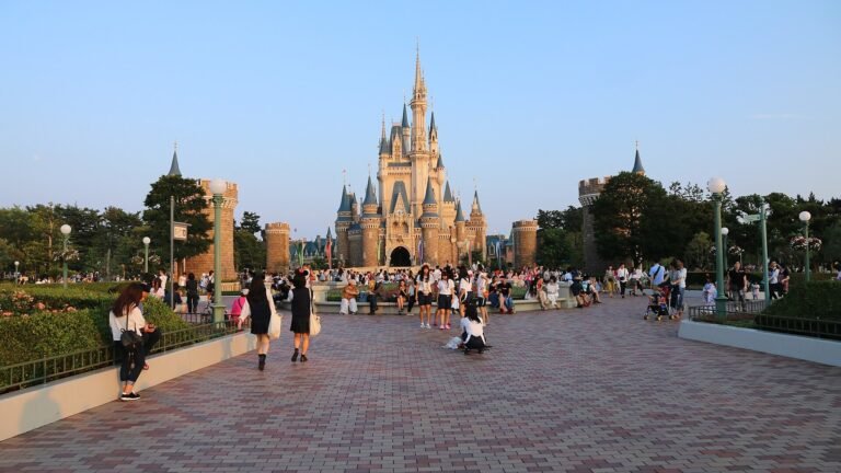 Cinderella Castle at Tokyo Disneyland viewed from the plaza in front, with visitors walking across the brick-paved square