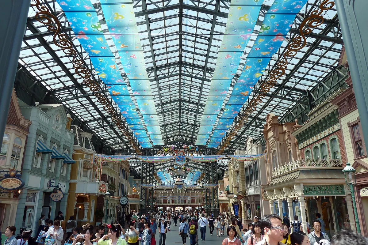 東京ディズニーランドのワールドバザール、ガラス屋根のアーケードに店が並びゲストでにぎわう様子