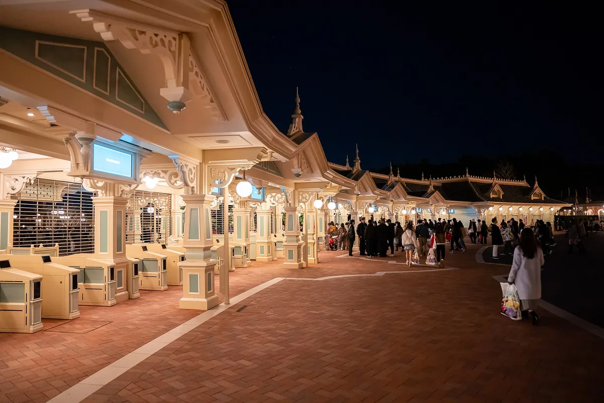 夜の東京ディズニーランドのメインエントランス。屋根のある入園ゲートと大勢のゲスト