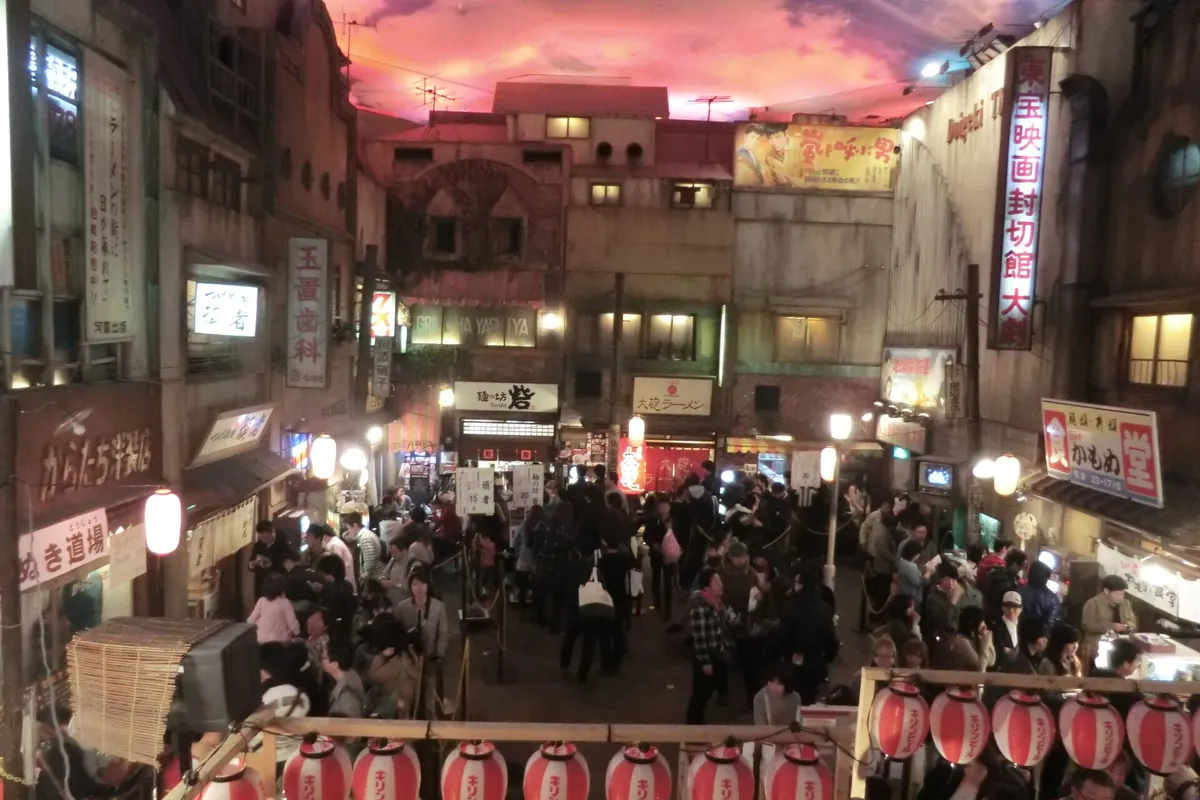 A recreated old Japanese street with ramen shop signboards, lanterns, and visitors inside the Shin-Yokohama Ramen Museum