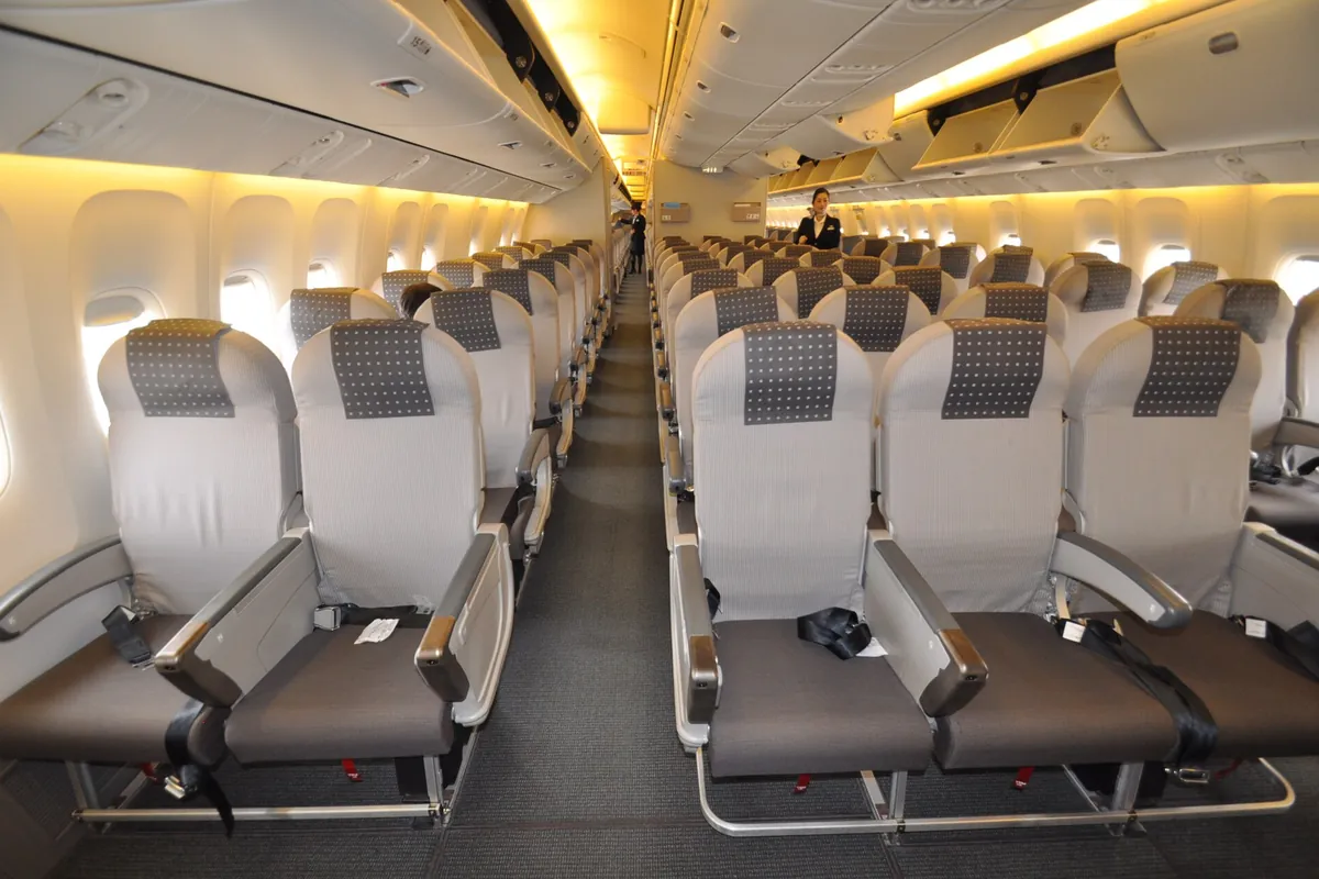 Rows of economy seats with dotted grey headrest covers in a Japan Airlines cabin